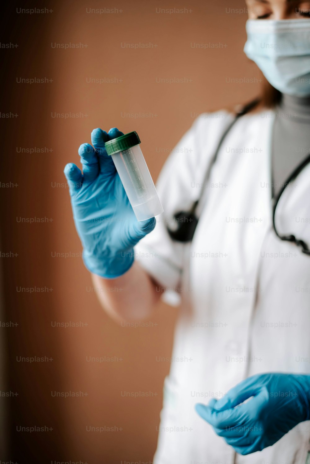 Una mujer con una bata blanca de laboratorio y guantes azules sosteniendo un tubo