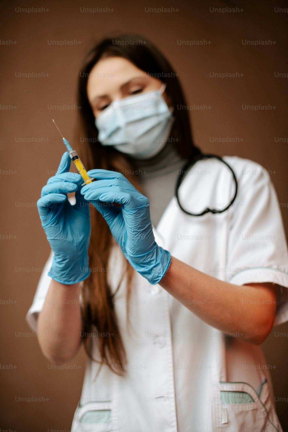 eine Ärztin im weißen Kittel und blauen Handschuhen