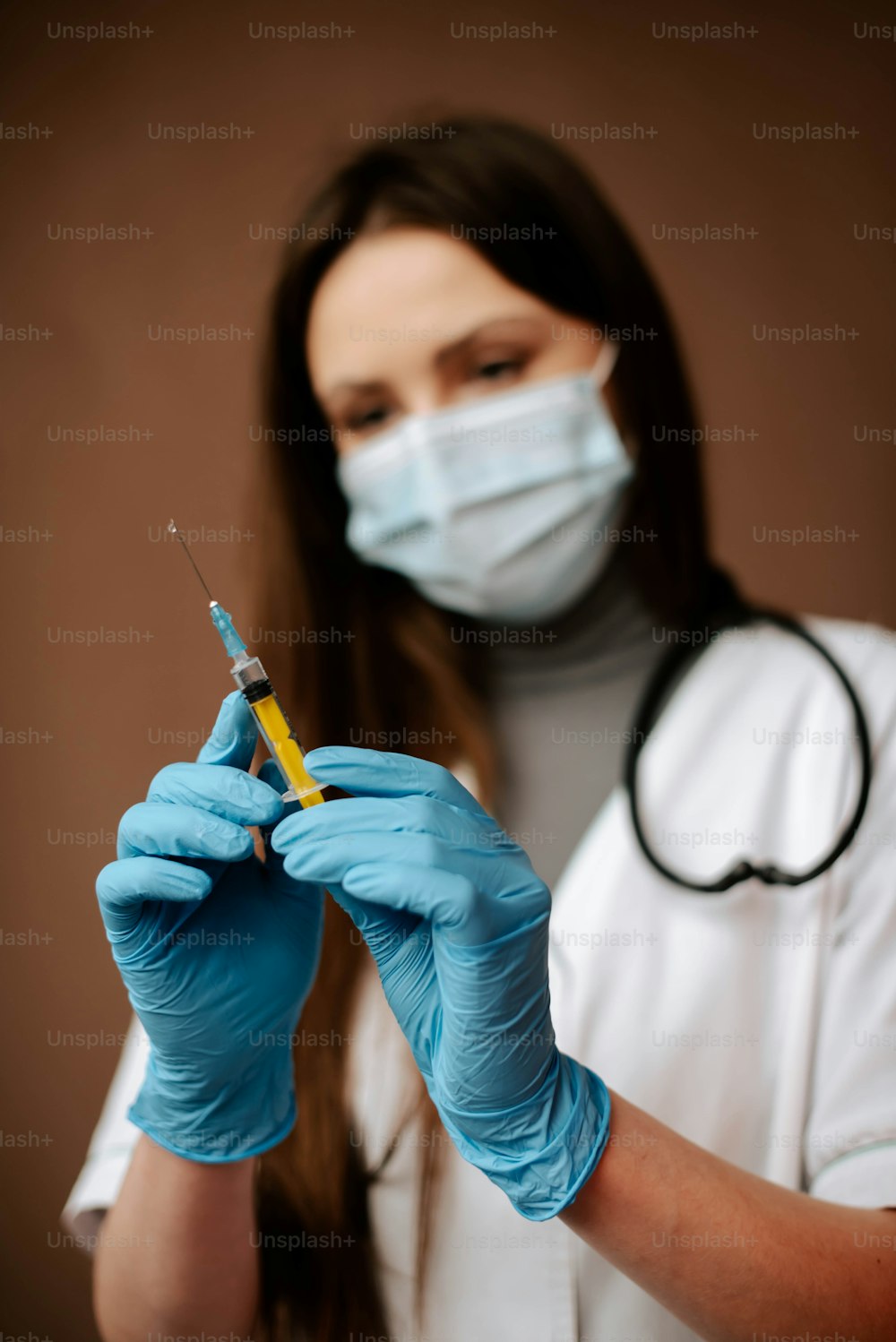 a woman in a white coat and blue gloves holding a sy