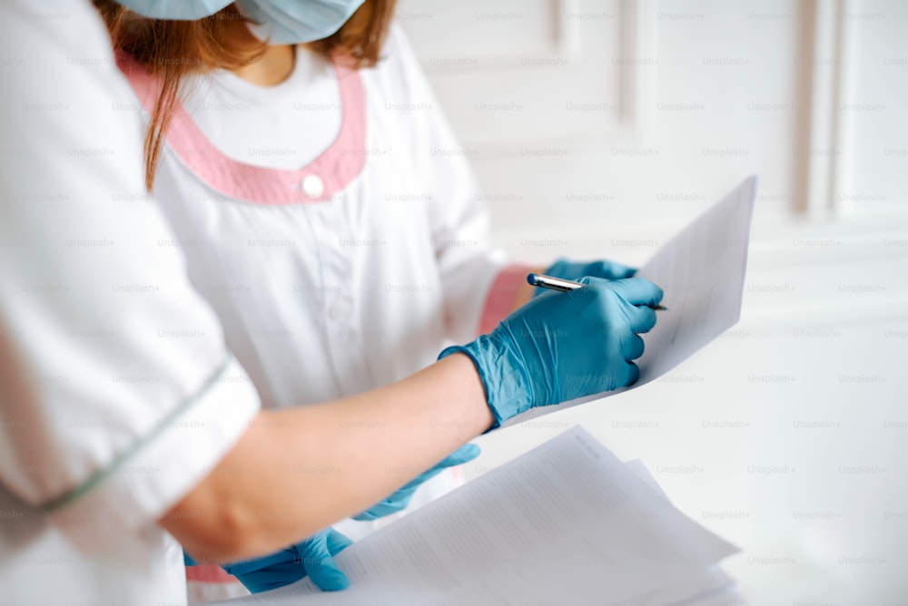 a woman in a white shirt and blue gloves holding a piece of paper