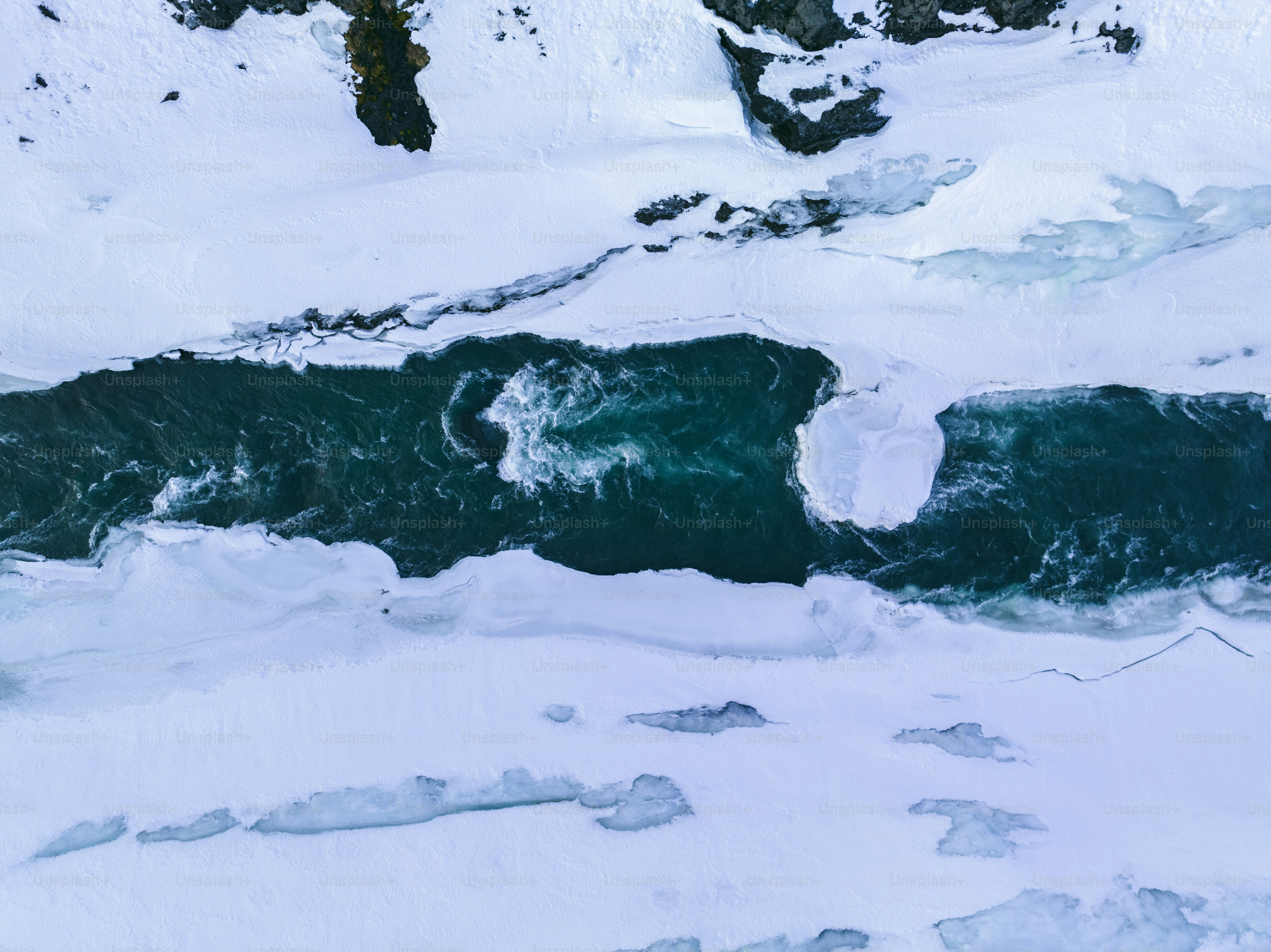 an aerial view of a river surrounded by snow