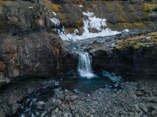 a small waterfall in the middle of a rocky area