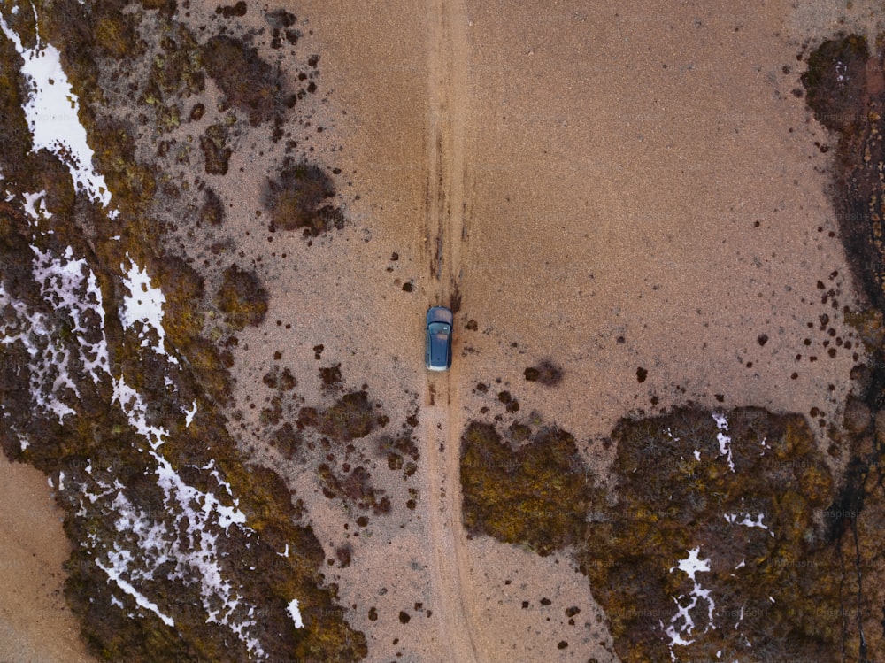 Una vista aerea di un'auto che guida su una strada sterrata
