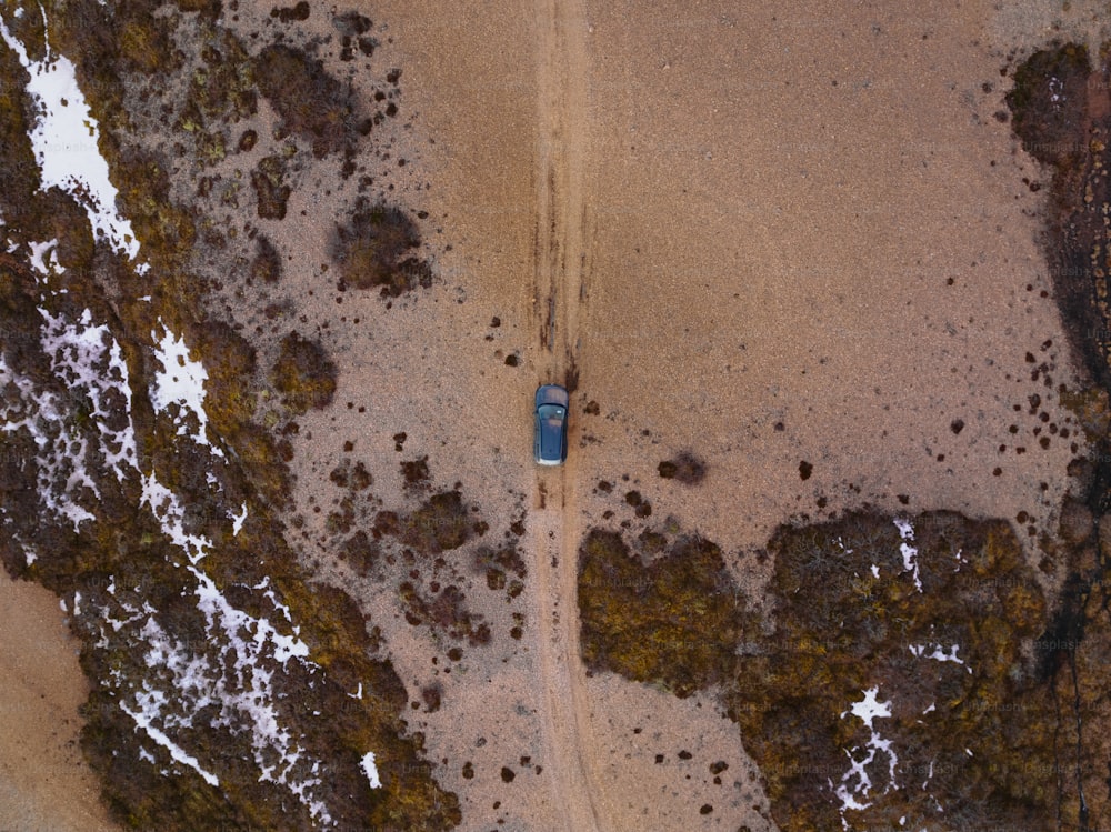 an aerial view of a car driving on a dirt road