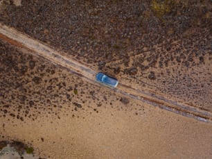 an aerial view of a car driving down a dirt road