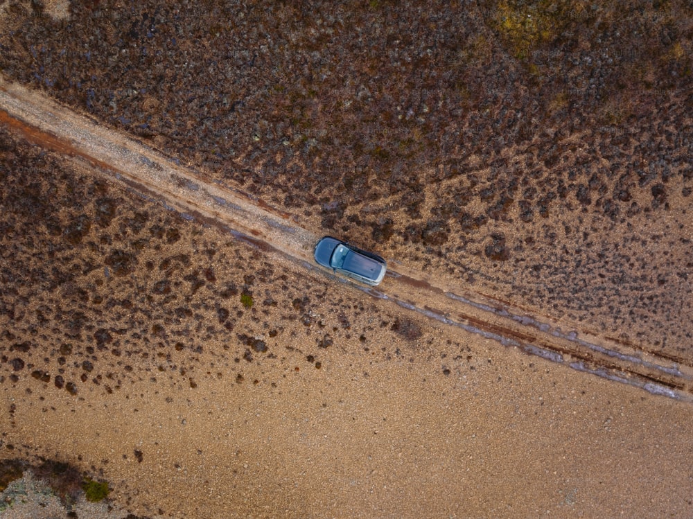 Una vista aerea di un'auto che guida lungo una strada sterrata