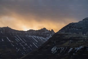 a mountain with snow on it and a cloudy sky