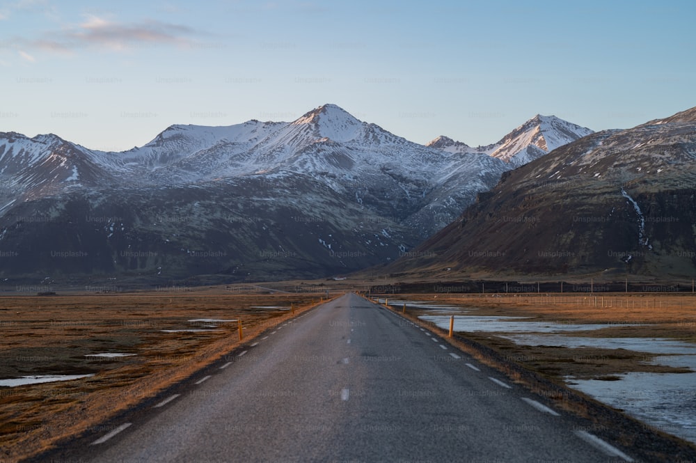 Eine Straße mitten auf einem Feld mit Bergen im Hintergrund