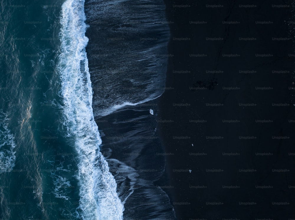 an aerial view of the ocean and a black sand beach