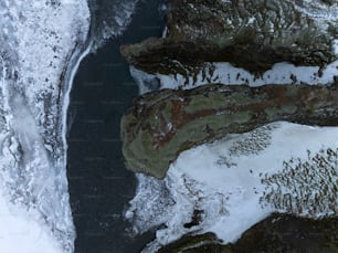 an aerial view of snow covered rocks and water