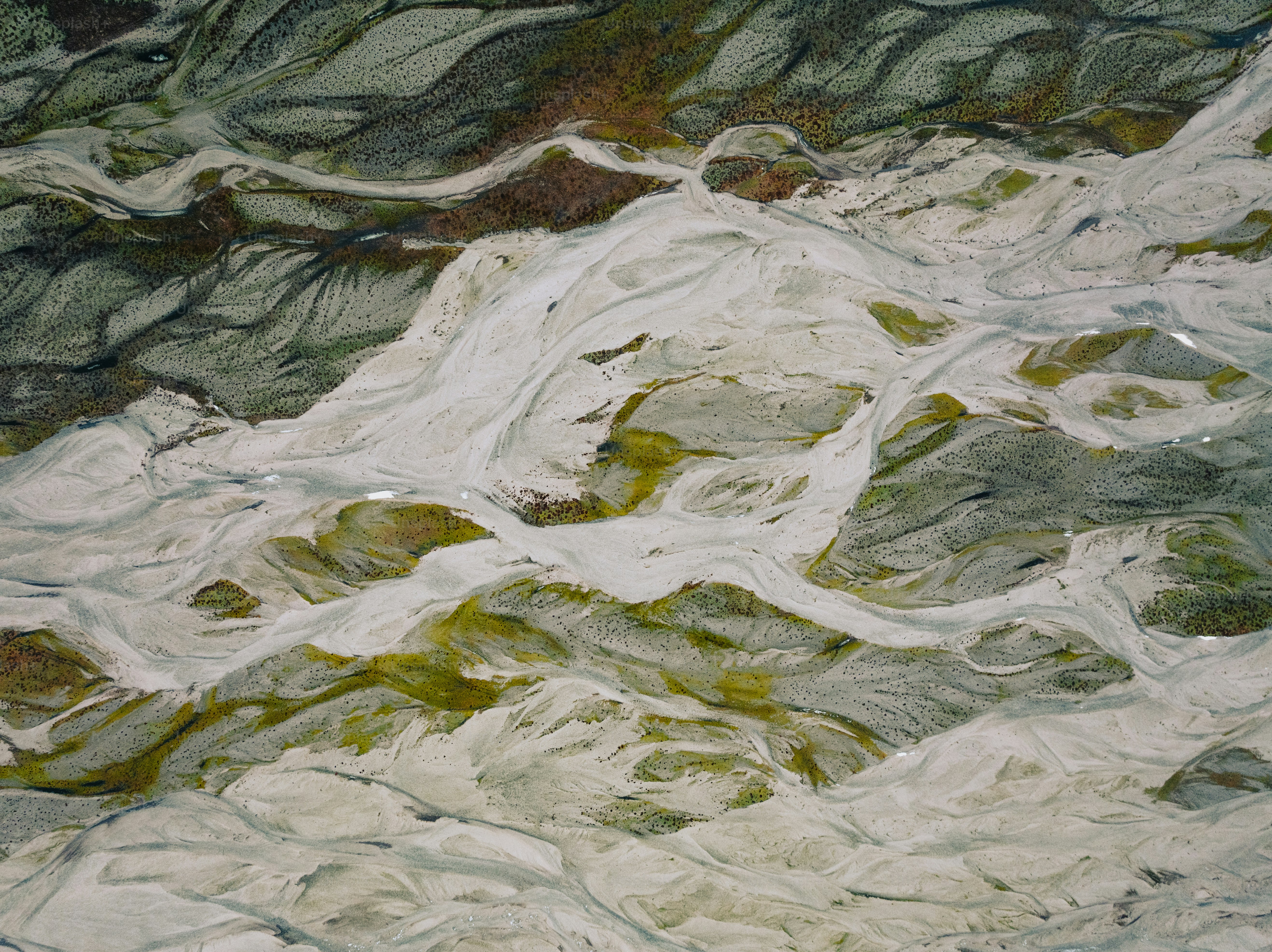 an aerial view of a mountain range with green and white rocks