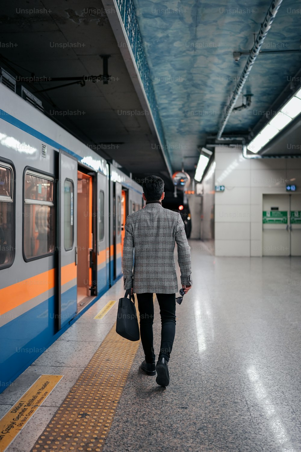 a man walking down a subway platform carrying a bag