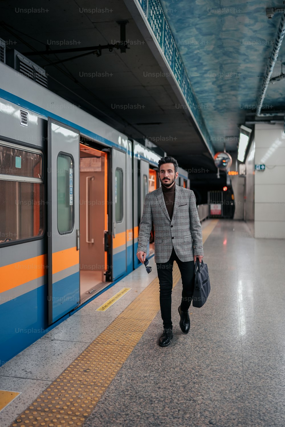 um homem de terno caminha por uma plataforma de metrô