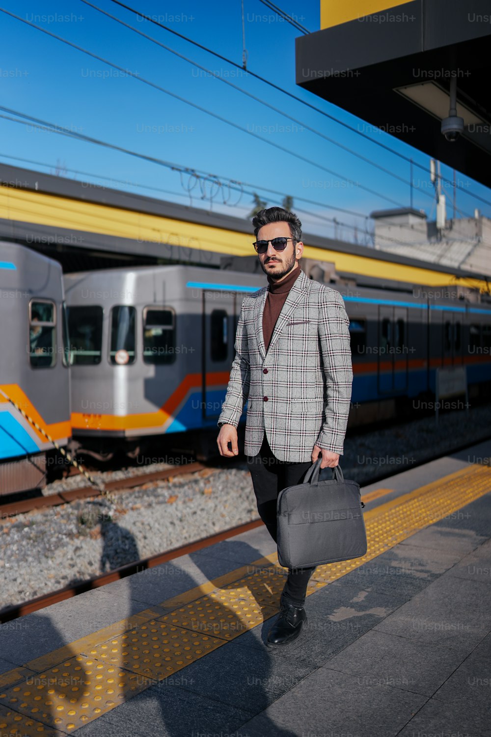 a man in a suit and sunglasses walking on a train platform