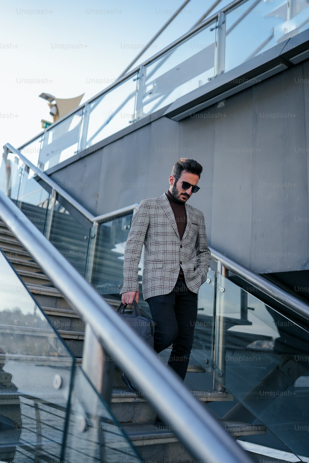 a man in a suit and sunglasses walking down a set of stairs