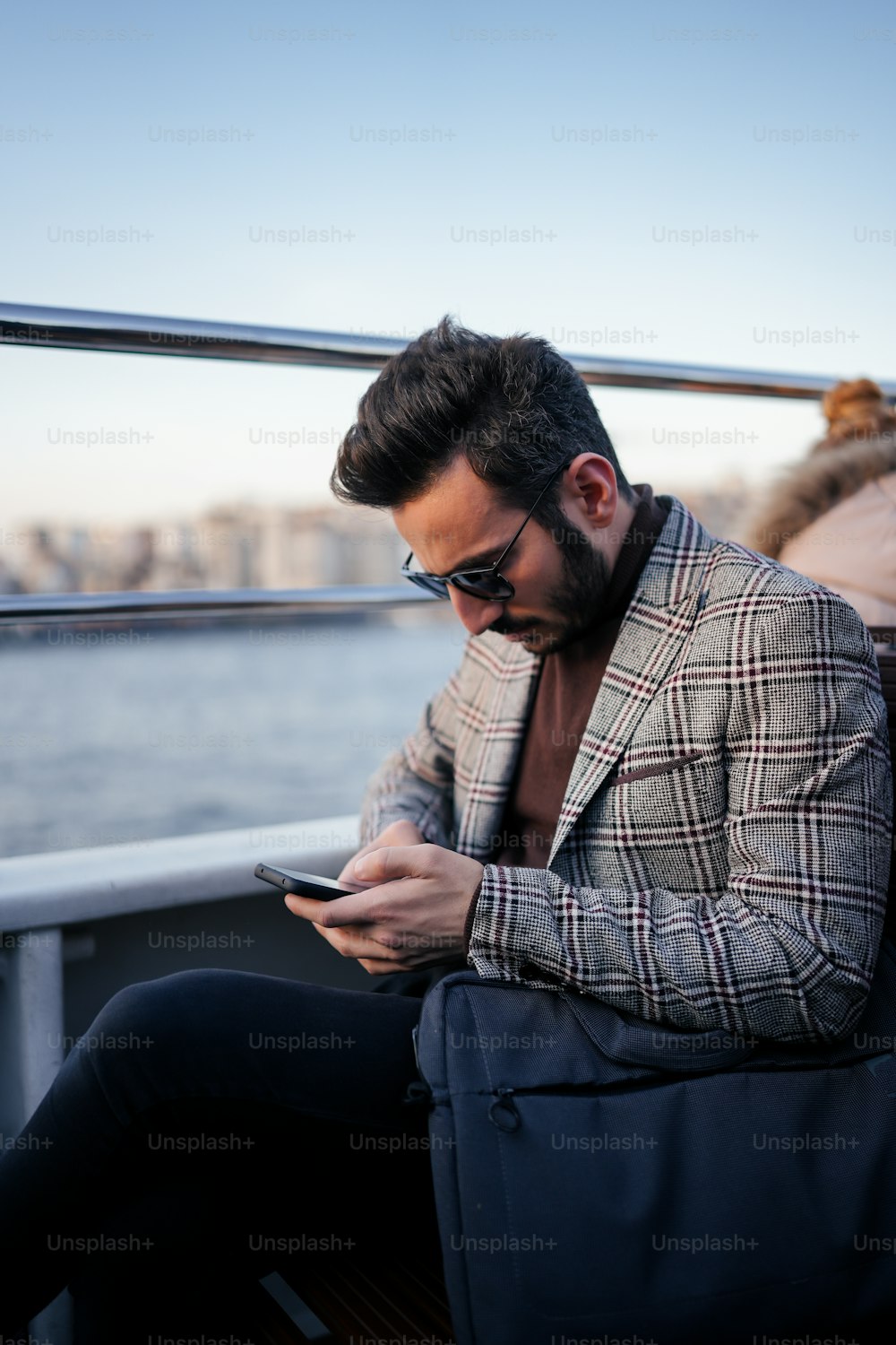 um homem sentado em um barco olhando para seu telefone celular