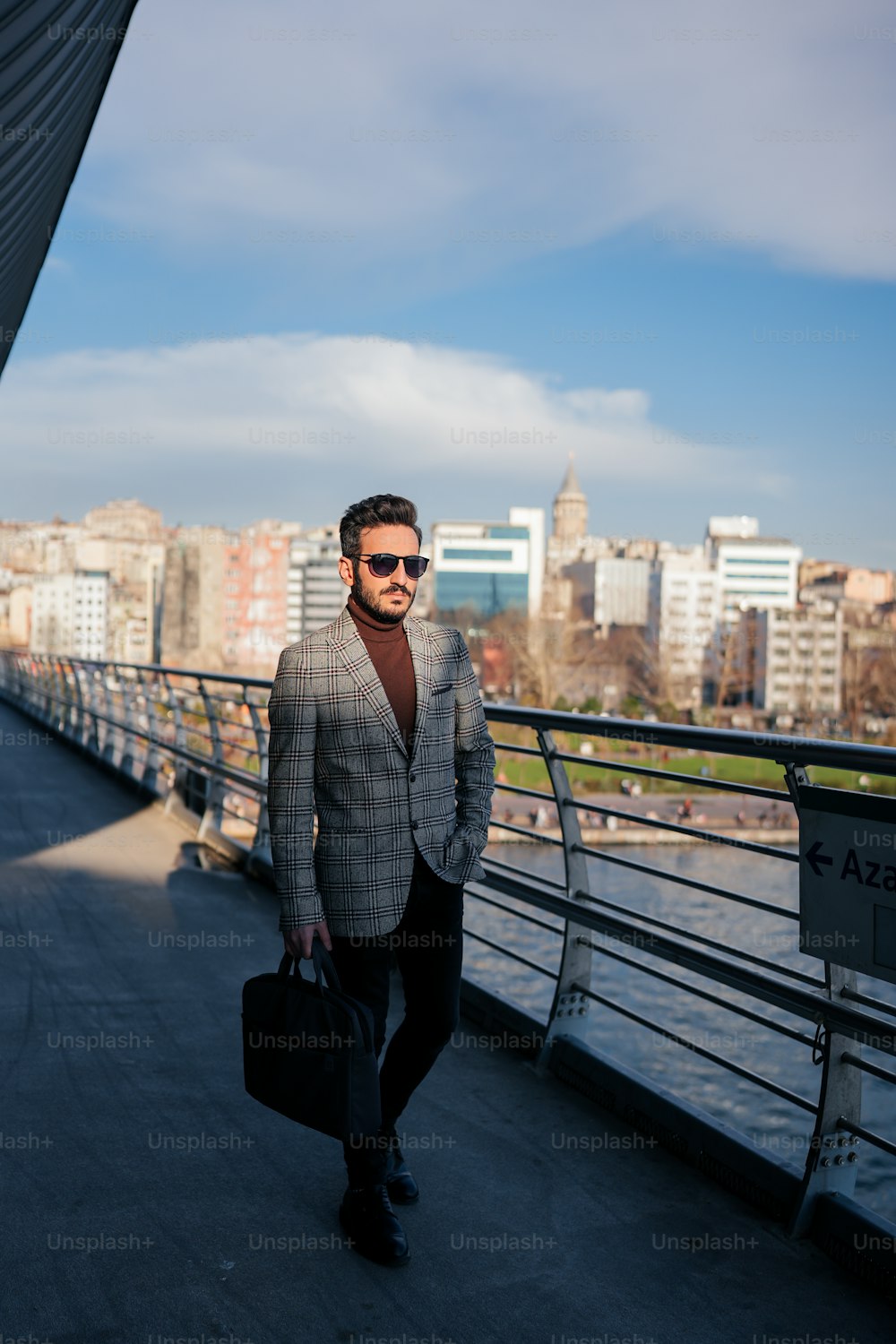 a man in a suit and sunglasses walking across a bridge