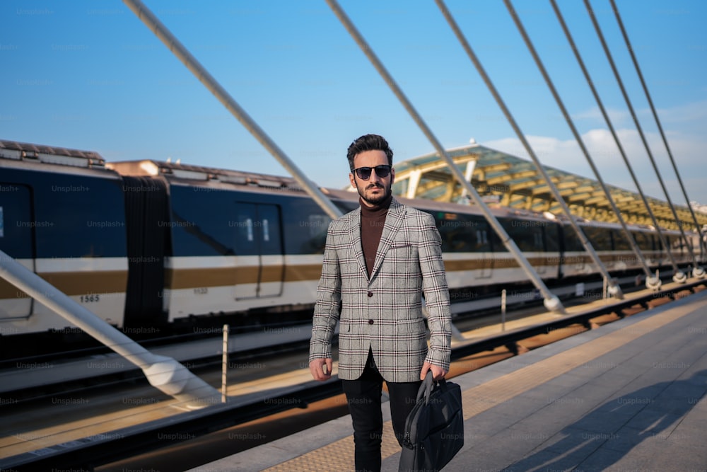 a man in a suit and sunglasses walking on a bridge