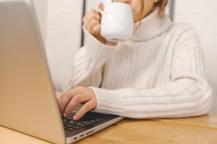 uma mulher que bebe café enquanto usa um computador portátil