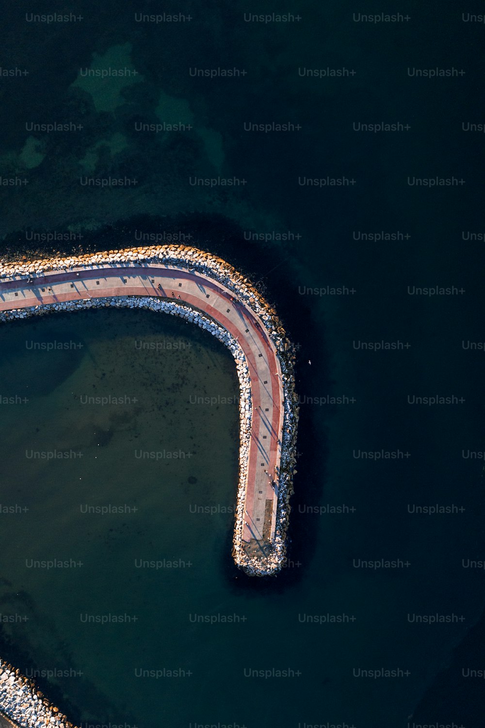 an aerial view of a curved road in the water