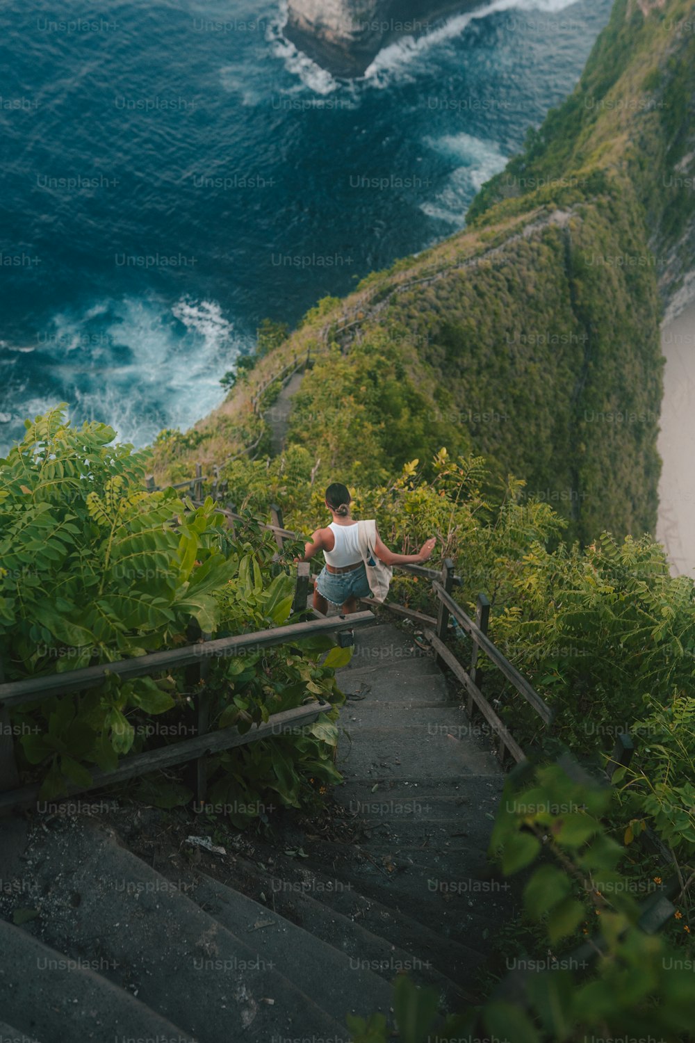 Un uomo seduto in cima a una serie di scale vicino all'oceano