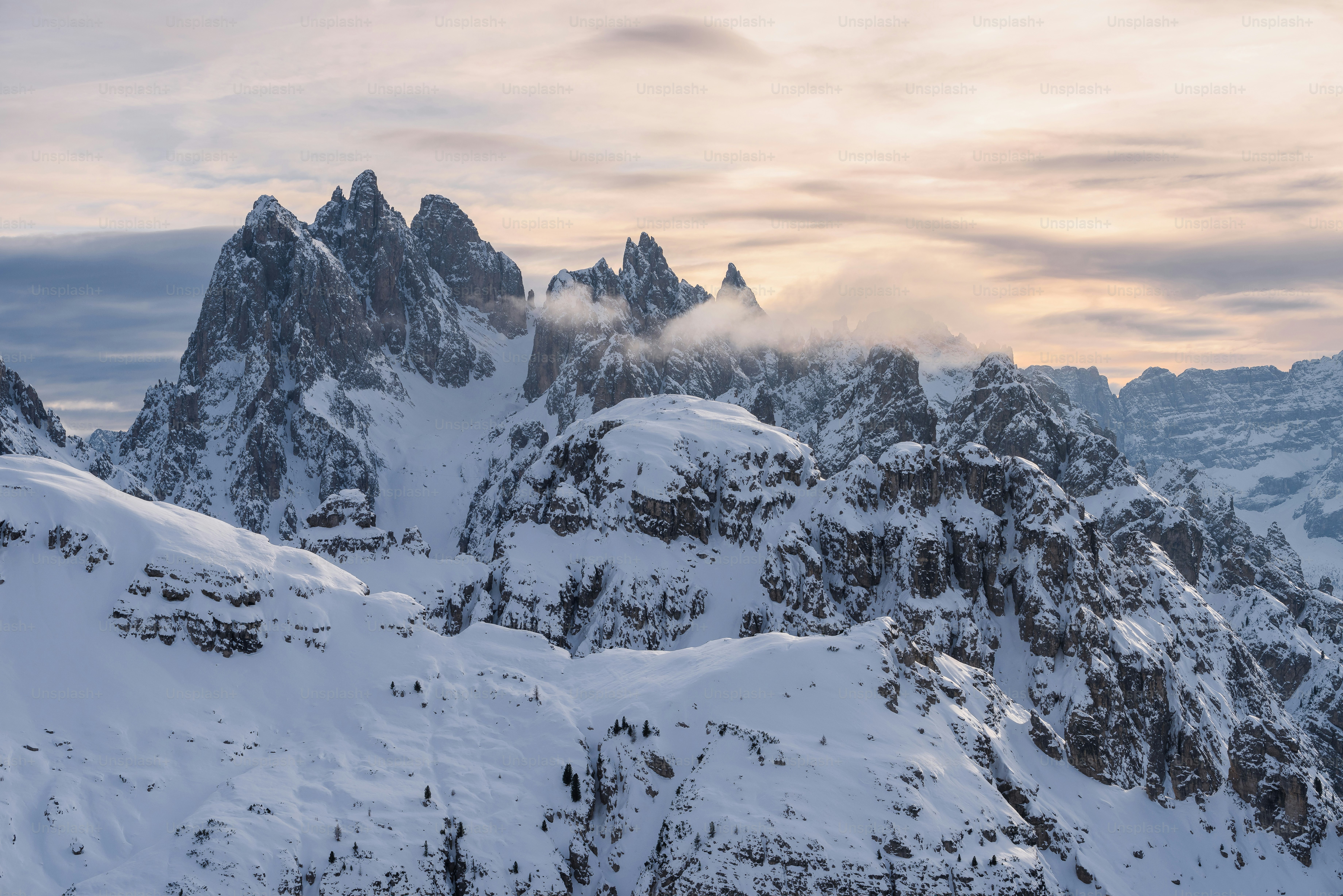 A mountain range covered in snow under a cloudy sky photo – Winter ...