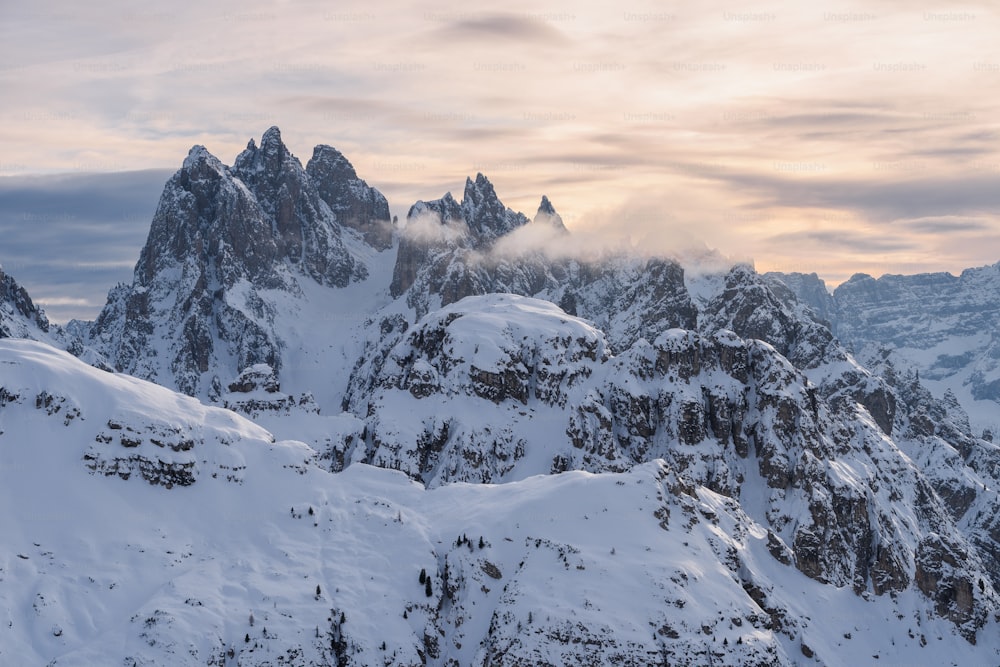 a mountain range covered in snow under a cloudy sky