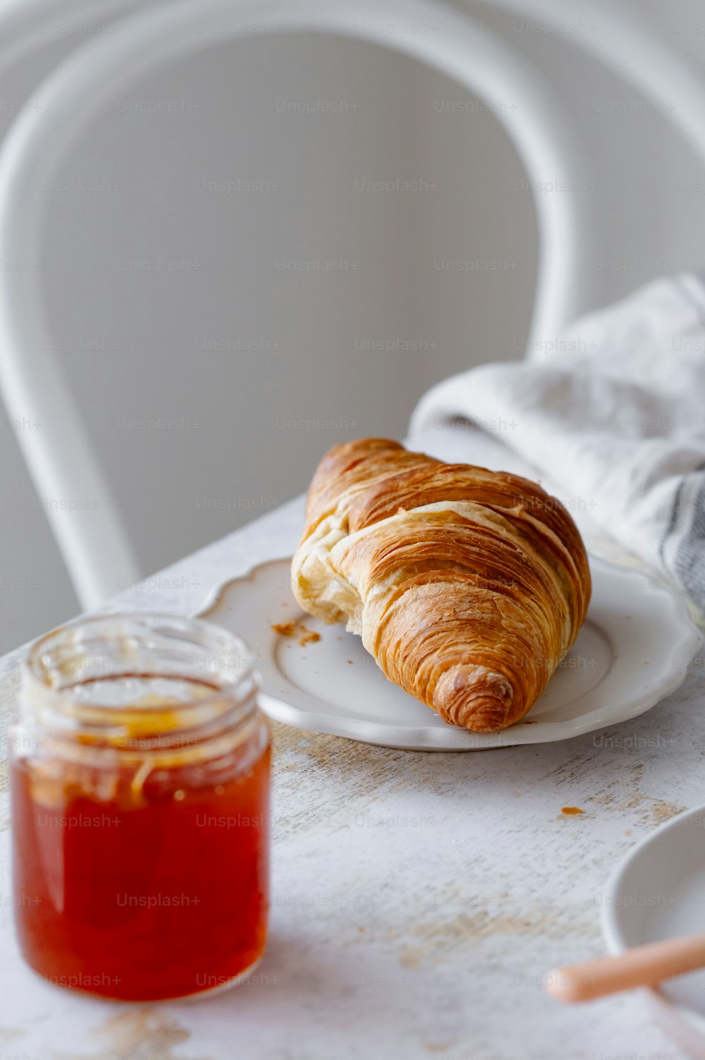 um croissant sentado em um prato ao lado de um frasco de mel