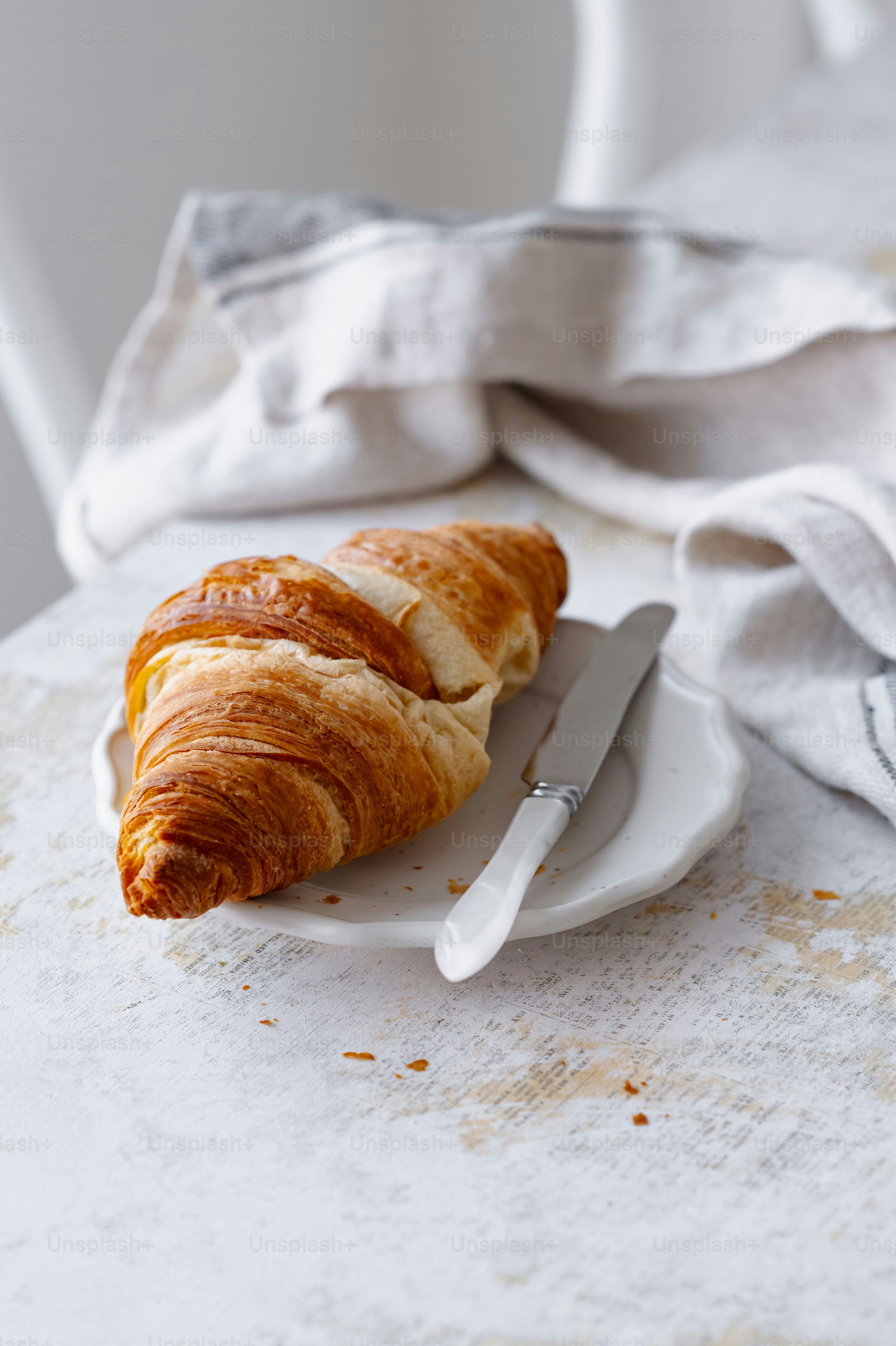 a croissant sitting on a plate next to a knife and fork