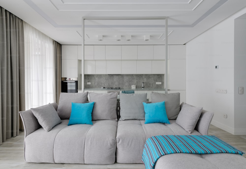 una sala de estar con un sofá gris y almohadas azules