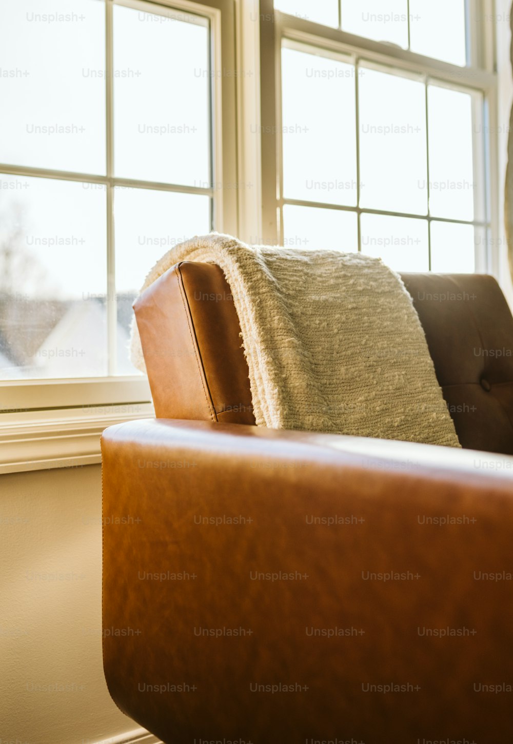 uma cadeira de couro marrom sentada na frente de uma janela