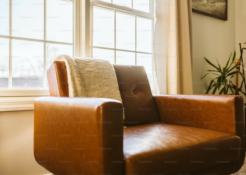 a brown leather chair sitting in front of a window