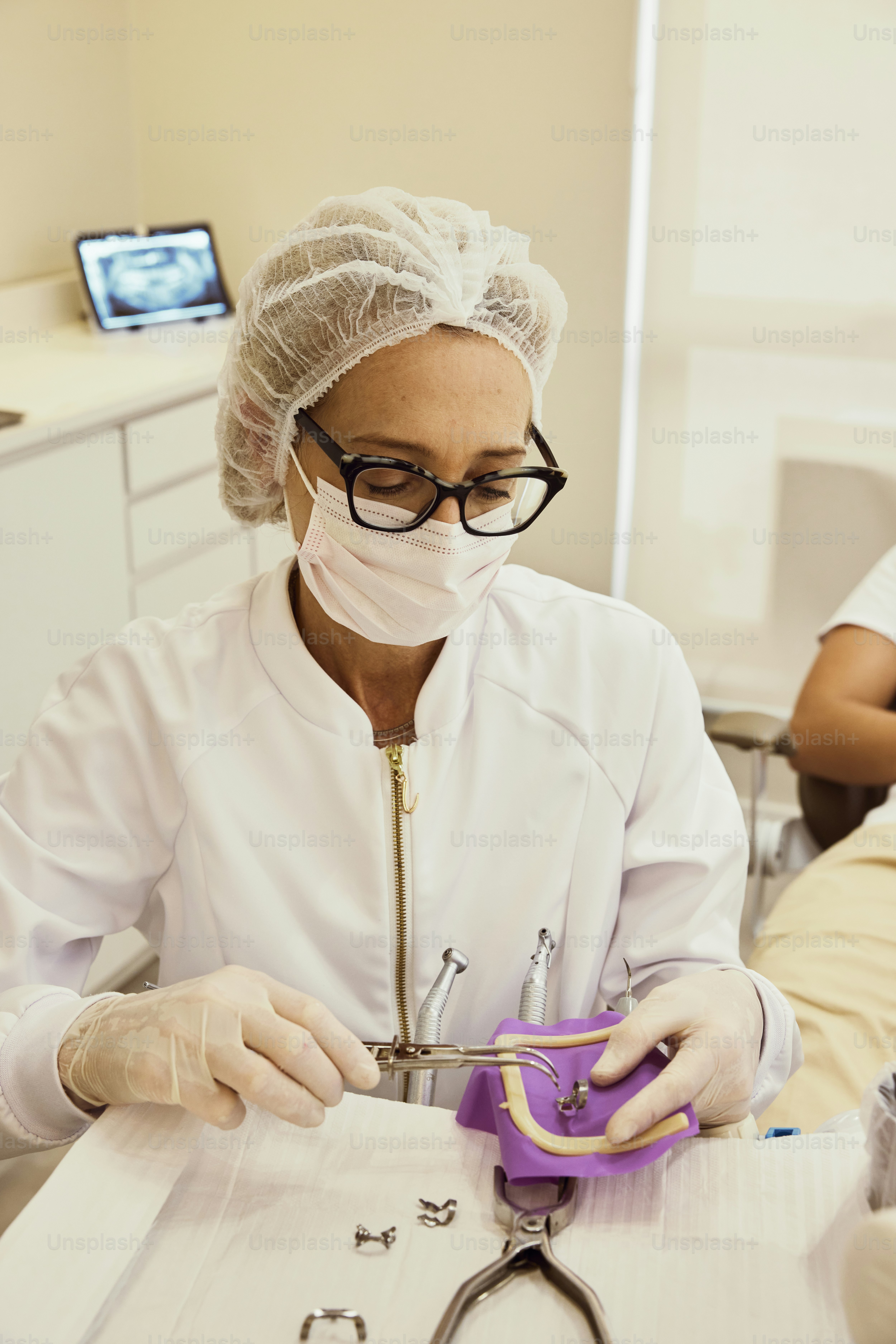 Una mujer con una bata blanca de laboratorio y gafas trabajando en un par de tijeras