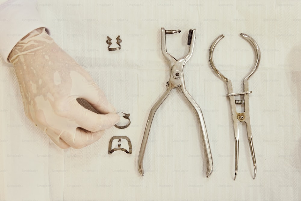 a person holding a pair of scissors next to a pair of pliers