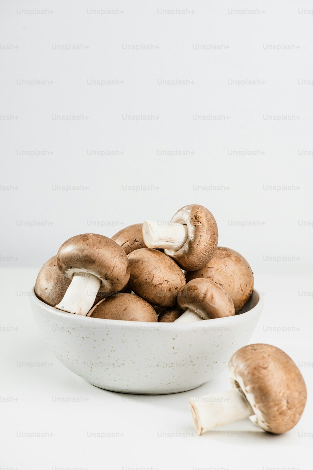eine weiße Schüssel gefüllt mit Pilzen auf einem Tisch