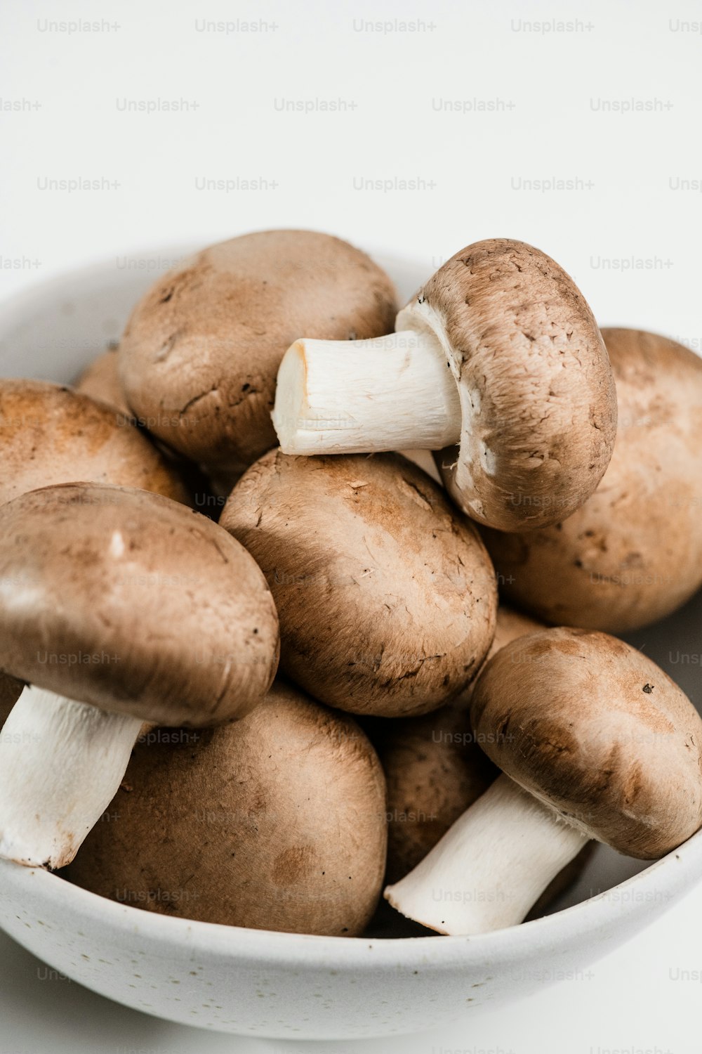 a white bowl filled with mushrooms on top of a table