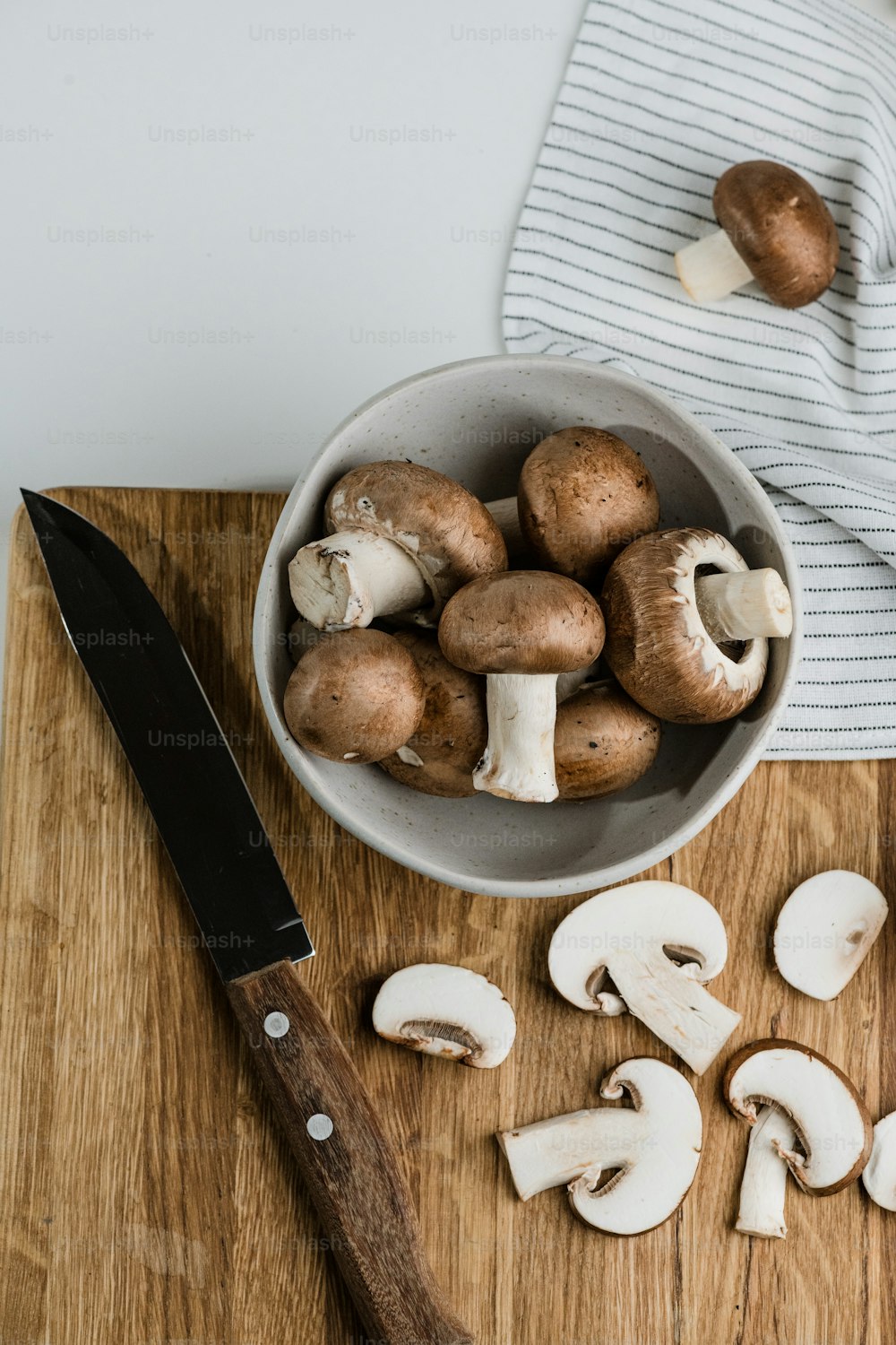 a bowl of mushrooms and a knife on a cutting board