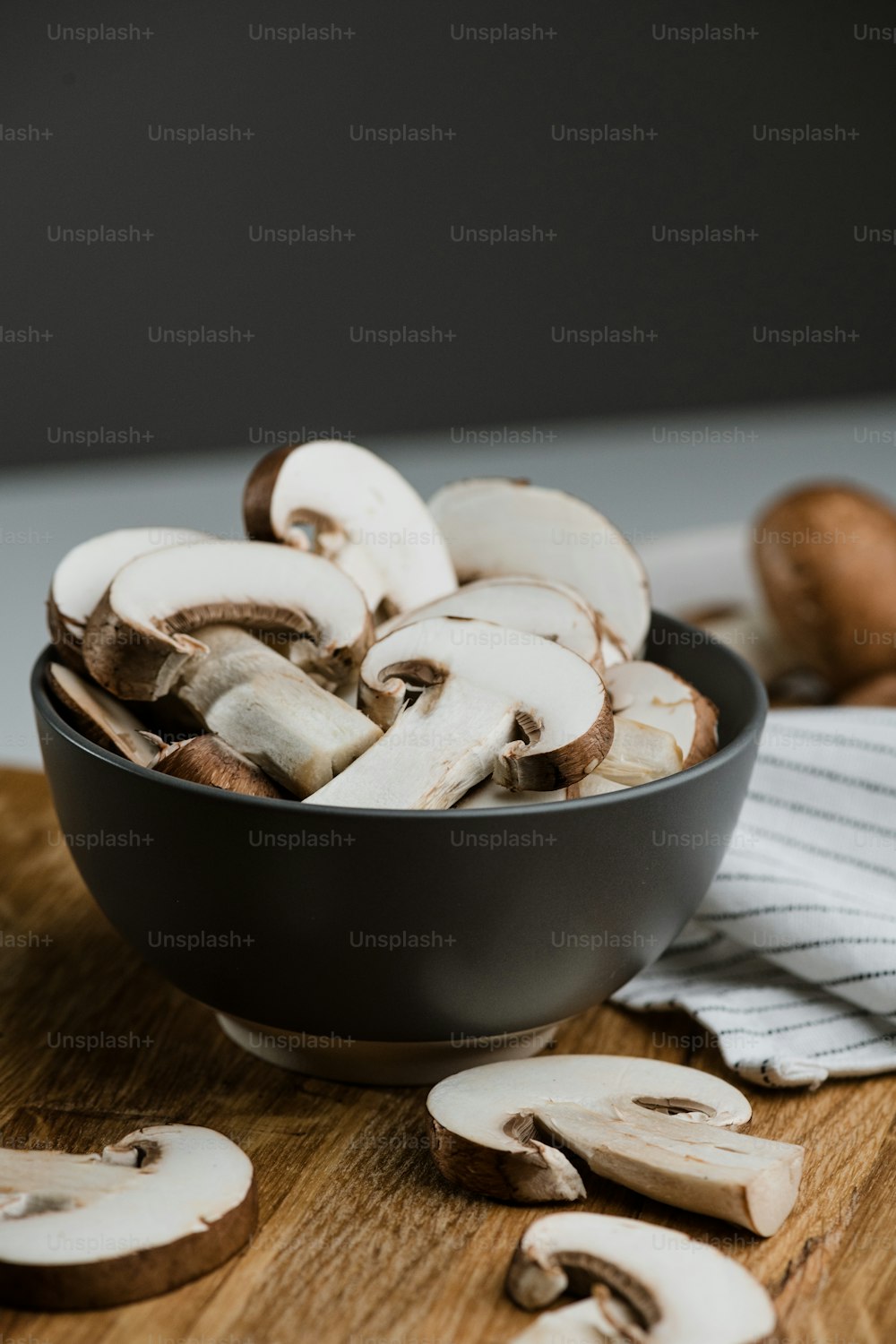 a bowl of sliced mushrooms on a cutting board