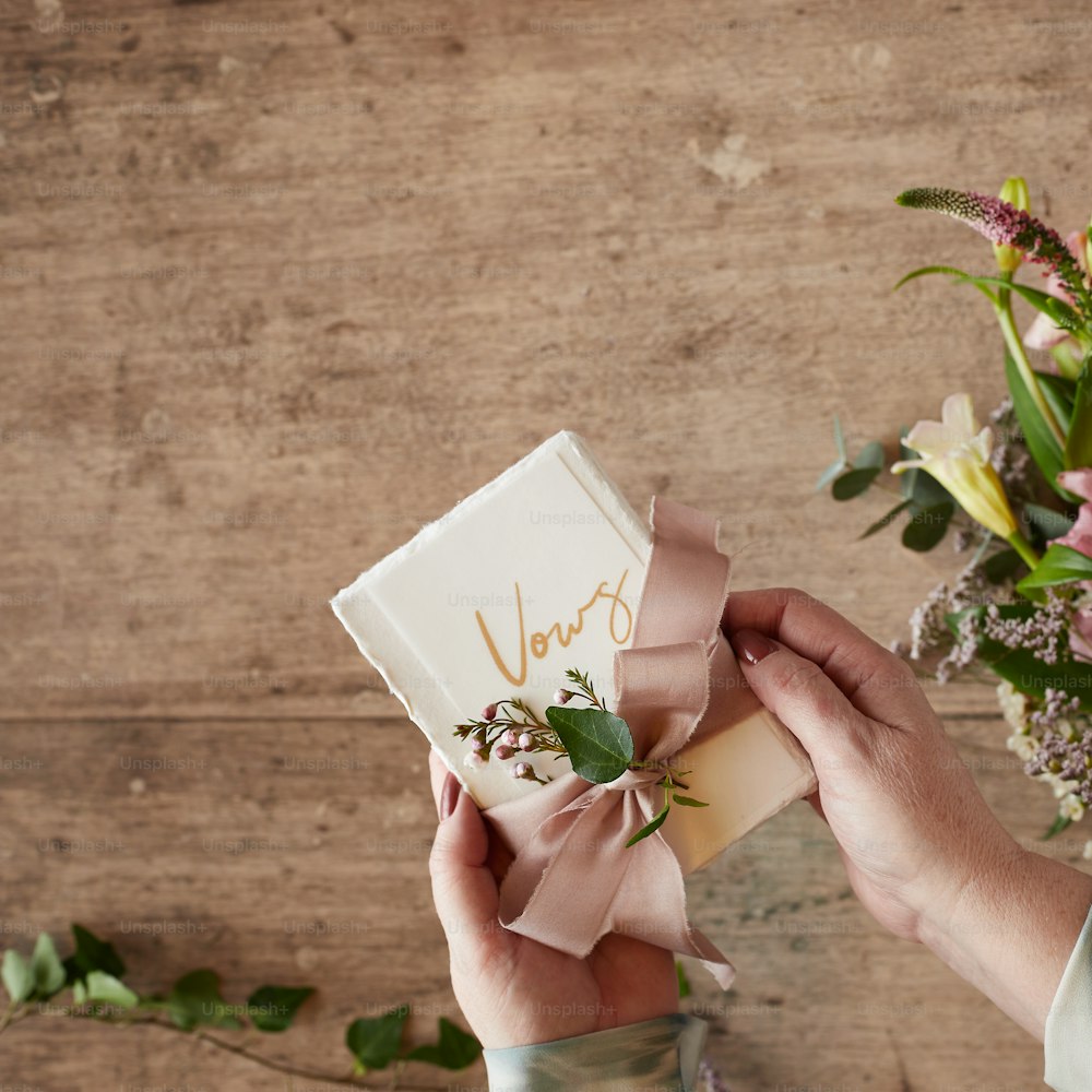 a person holding a small gift box with flowers