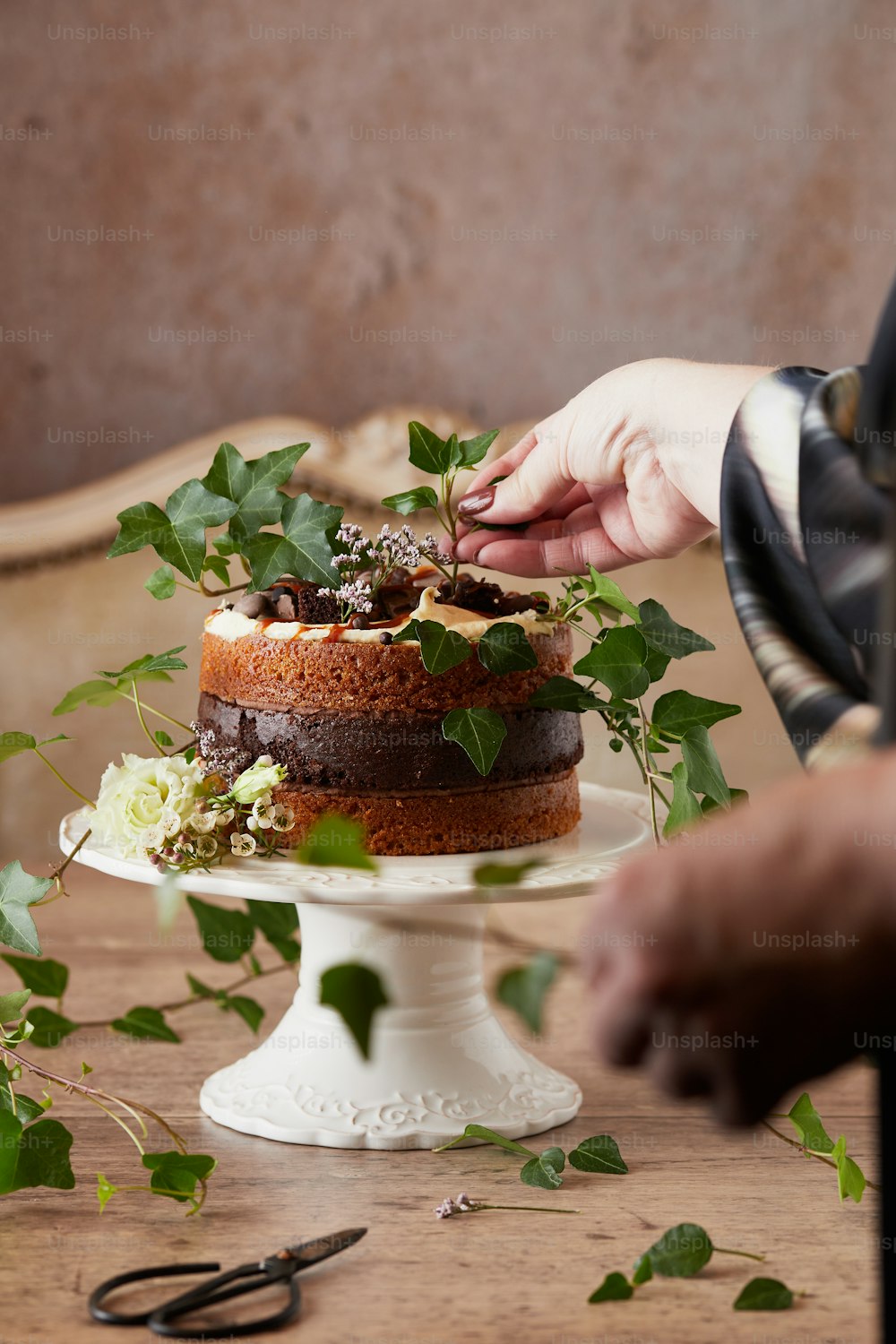a person decorating a cake with greenery on a table