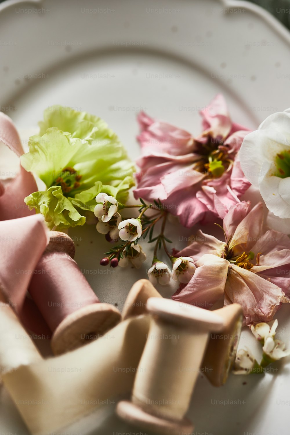 un piatto bianco sormontato da fiori rosa e verdi