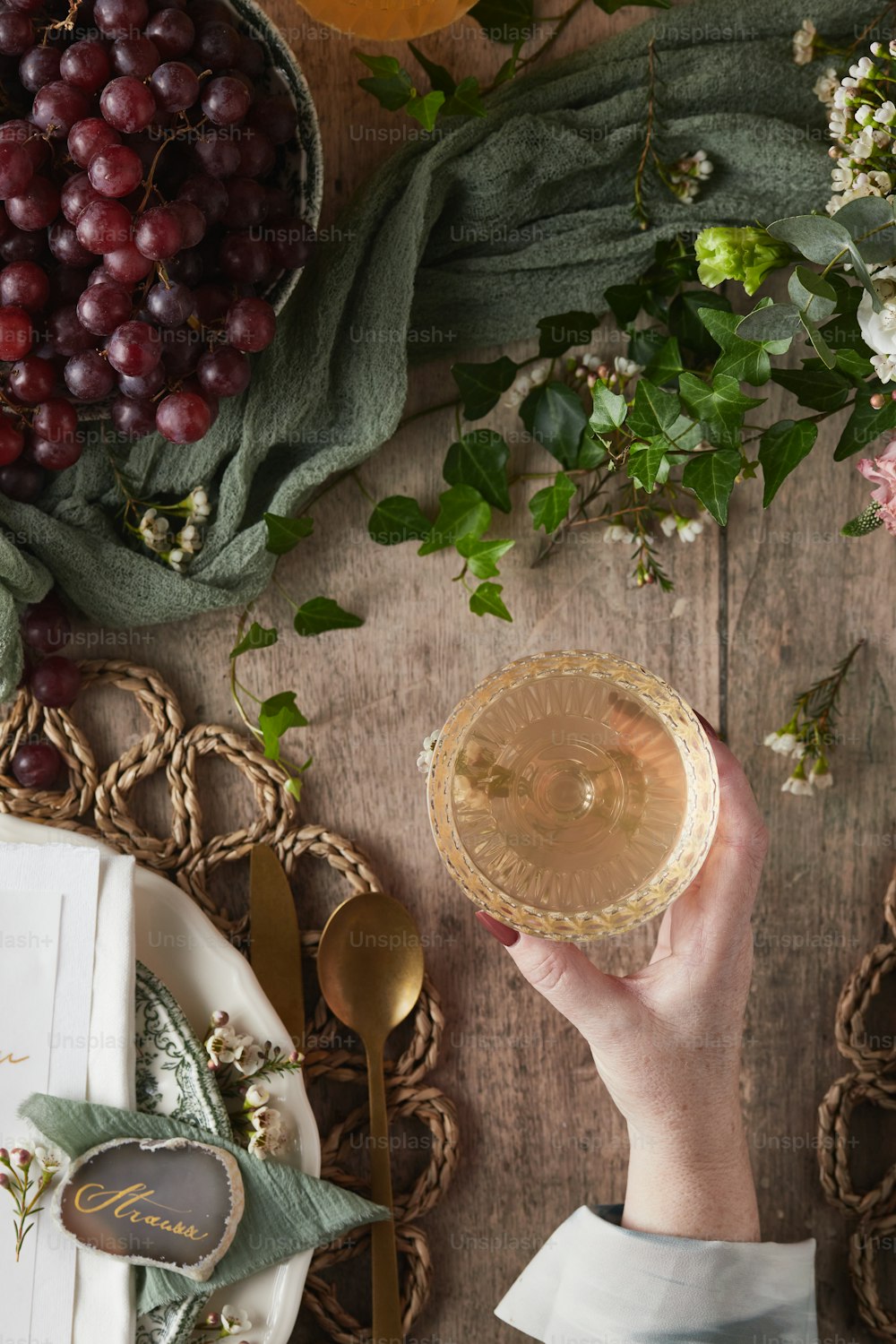 a person holding a wine glass in front of a bunch of grapes