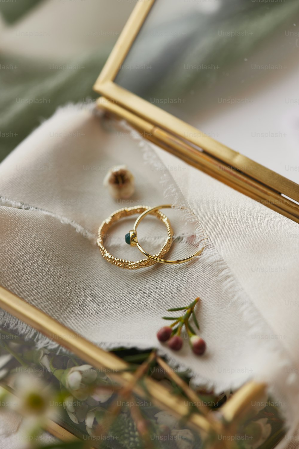 a pair of gold wedding rings sitting on top of a white cloth