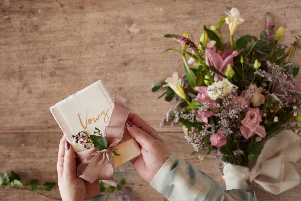 uma pessoa segurando um cartão com um buquê de flores no fundo