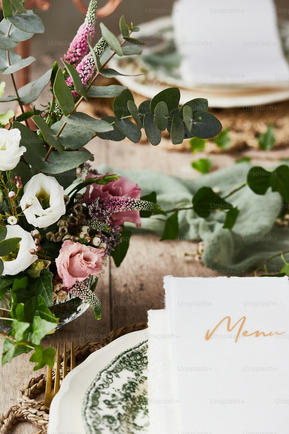 a table setting with a menu and flowers in a vase