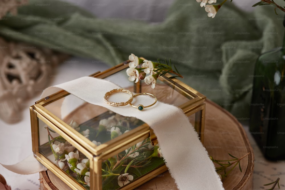 Un par de anillos de boda sentados encima de una caja de vidrio