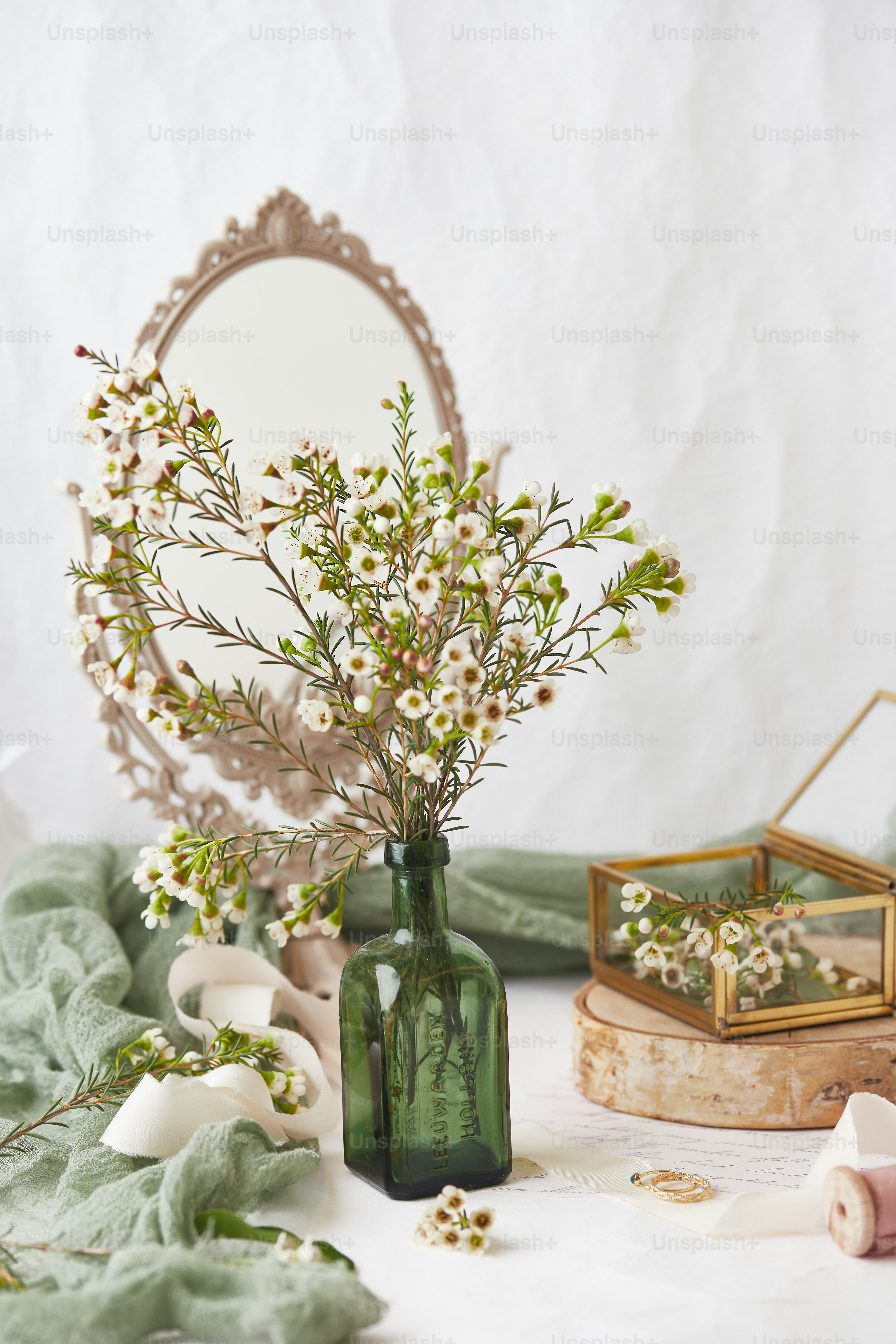 eine Vase mit Blumen und einem Spiegel auf einem Tisch