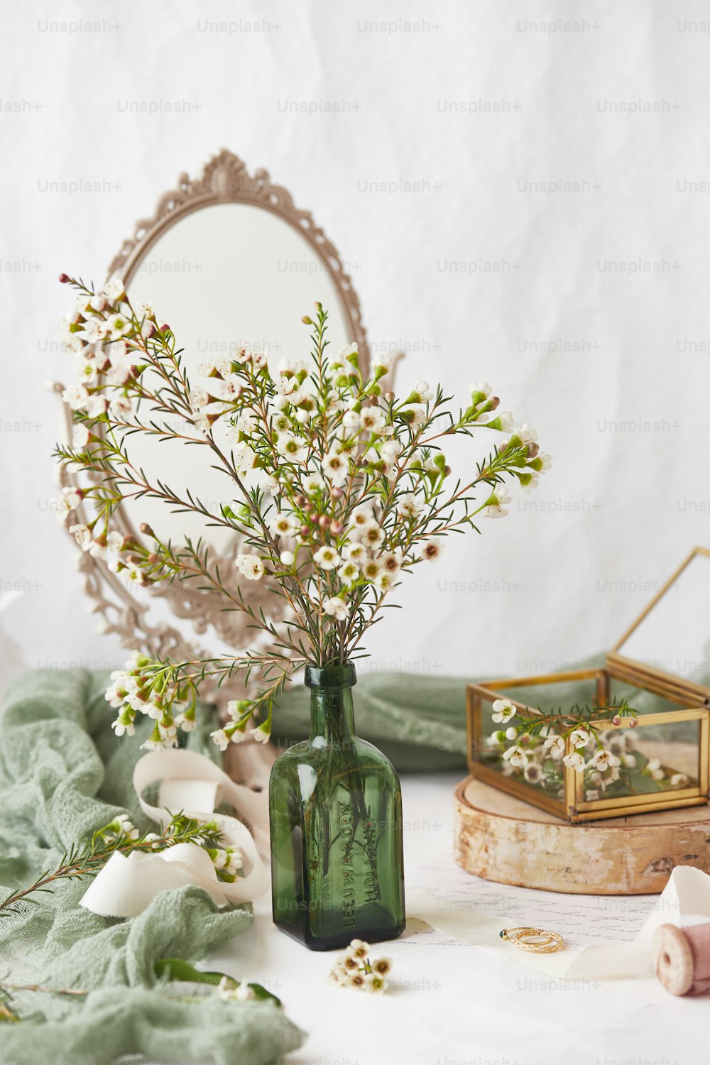 eine Vase mit Blumen und einem Spiegel auf einem Tisch
