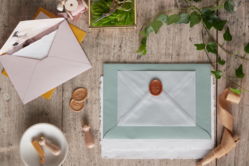 Une enveloppe avec un timbre de cire se trouve sur une table à côté d’une plante en pot