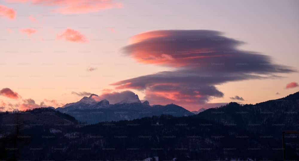 Una vista del atardecer de una cadena montañosa con nubes en el cielo